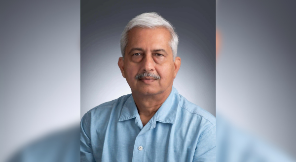 Portrait of Hirenkumar Jani, M.D. Older man with short white hair and mustache, wearing a blue collared shirt, poses against a gradient gray background with a calm expression.