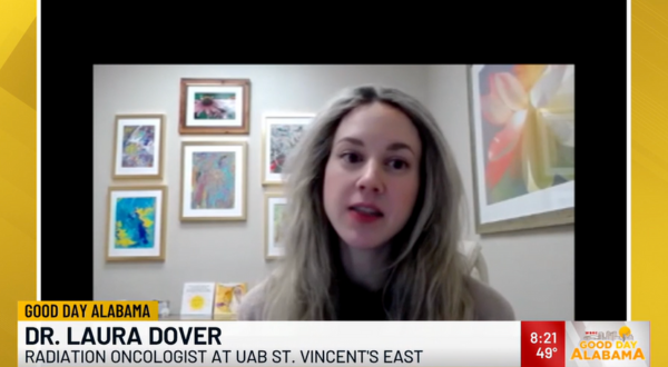 Dr. Laura Dover, a radiation oncologist, appears on "Good Day Alabama" via video call. Behind her, colorful abstract art decorates a neutral-toned wall.