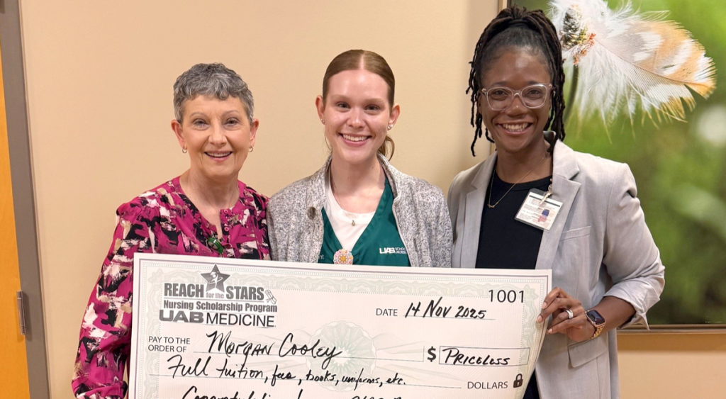 Three women smiling and holding a large ceremonial scholarship check for Morgan Cooley from the Reach for the Stars Nursing Scholarship Program.
